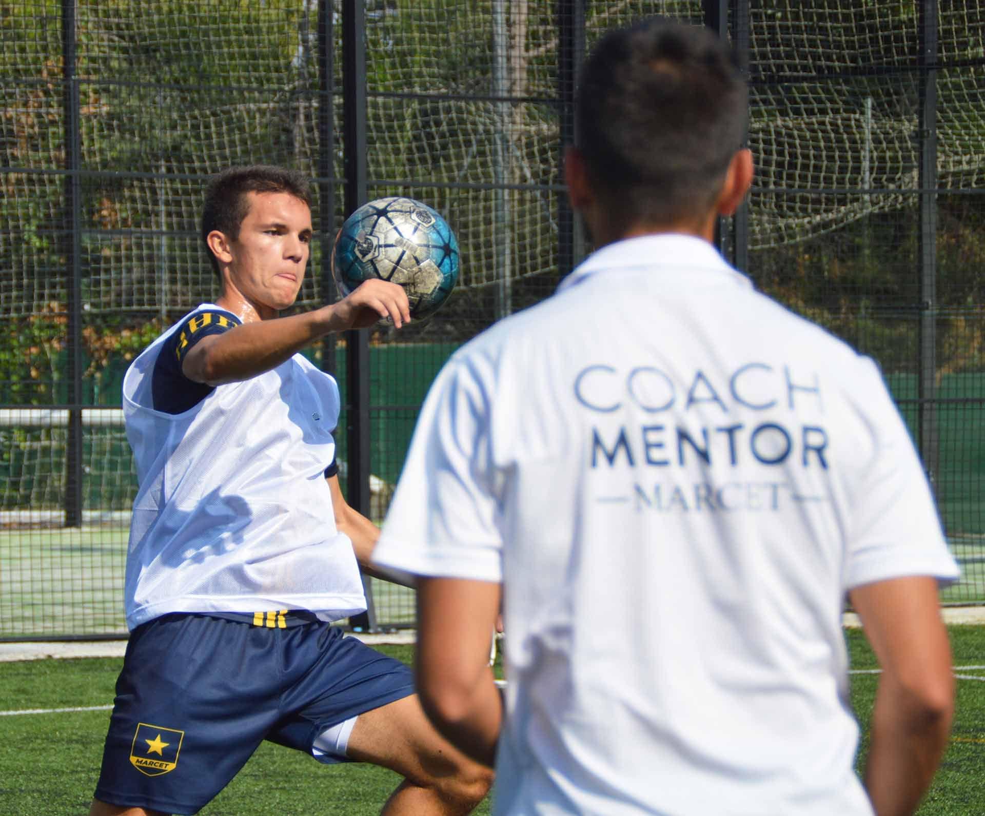 Marcet Football Academy student kicks a blue and silver football in front of coach mentor.
